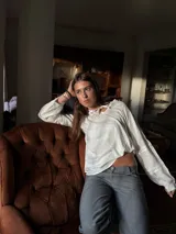 Camisa blanca de manga larga con escote a la base y detalles de blonda en cuello y mangas.