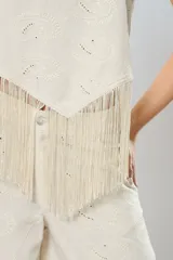 Blusa beige de lino bordado, sin mangas y con terminación en flecos.