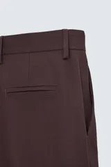 Pantalón de vestir color marrón oscuro, de corte recto, con bolsillos laterales y traseros de doble vivo. Se ajusta a la cintura con cierre de cremallera y botón.