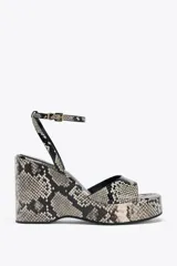 Sandalias de cuña con plataforma y estampado de serpiente en tonos grises y negros. Tira delantera ancha y tira trasera con hebilla metálica. Tacón de 10 cm y punta cuadrada.