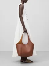 Bolso tipo shopper grande color marrón con textura granulada. Tiene un compartimento principal con cierre magnético y un bolso interior extraíble con cierre de cremallera. El asa de hombro tiene una hombrera y el logo está grabado.