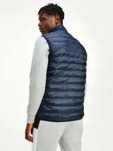 Chaleco acolchado azul marino con cierre de cremallera, cuello alto y logo de Tommy Hilfiger bordado en el pecho.