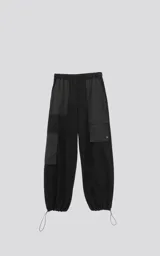 Pantalón tipo jogger negro, de calce relajado, confeccionado en algodón y microfibra. Presenta paneles de microfibra en la parte superior y bolsillos cargo con fuelle en las piernas. Los tobillos son ajustables con cordón elástico.