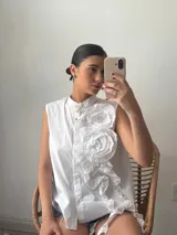 Camisa blanca sin mangas con cuello mao y volados en el frente.