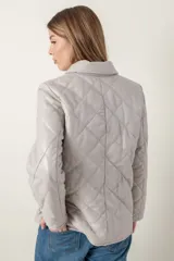 Campera de cuero negra con diseño matelassé de rombos, cuello camisero, cierre frontal con botones a presión, dos bolsillos delanteros y puños con botón.
