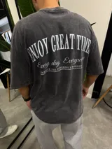 Remera gris con efecto lavado, corte holgado y estampa en la espalda con la frase "Enjoy Great Time".