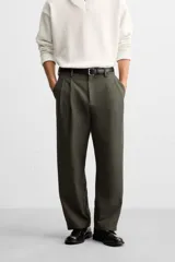 Pantalón verde oliva de corte amplio con pliegues en la parte delantera, bolsillos laterales y traseros de ojal.