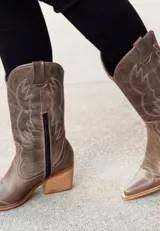 Bota texana de cuero color marrón, con caña media, punta fina y taco de madera.