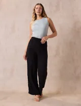 Pantalón negro de rayón con bordados florales, pretina ancha elastizada en punto smock y corte palazzo. Marca Liv Los Angeles.
