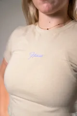 Remera corta color beige con logo estampado en el frente, de algodón elastizado y corte ajustado.