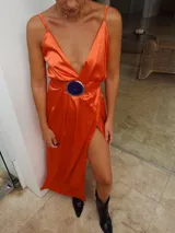 Vestido largo de satén color naranja, con escote en V, tajo lateral y cinturón con hebilla de alpaca y piedra ágata.