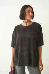 Remera gris con mangas cortas, cuello redondo y estampado con diseño abstracto en el frente.