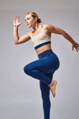 Top deportivo color beige con banda inferior azul y tirantes finos azul marino. Espalda cruzada con doble tira.