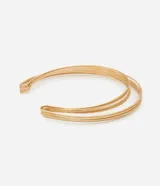 Gargantilla rígida y abierta de metal con baño dorado claro, con diseño de múltiples hilos paralelos en formato de luna.