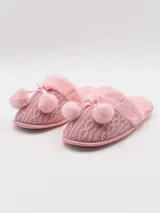 Pantuflas rosadas de tejido de punto trenzado, con borde de piel sintética y pompón decorativo con lazo.