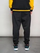 Pantalón de jogging negro con puños ajustados y logo del Club Atlético Peñarol bordado en dorado.