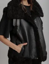Chaleco negro con forro de peluche, bolsillos delanteros y doble hebilla en el cuello.