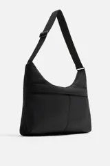 Bolso de hombro color verde oliva, fabricado en tejido técnico acolchado. Tiene un compartimento principal con cierre de cremallera, un bolsillo interior con cremallera y un bolsillo frontal con cremallera. El asa de hombro es ajustable.