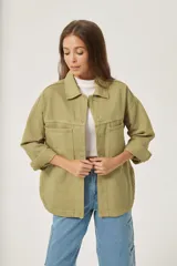 Sobrecamisa color verde militar con cuello camisero, cierre frontal con botones a presión, mangas largas con puños abotonados, dos bolsillos de parche en el pecho y corte holgado.