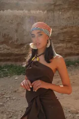 Top marrón con espalda descubierta y tiras para atar al cuello. Presenta una arandela amarilla en el centro del busto.