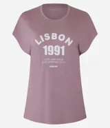 Remera deportiva de modal color lila con cuello redondo y mangas cortas. Estampa frontal con la leyenda "Lisbon 1991. Live like your life depends on it. Europe".