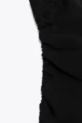 Top negro strapless de tejido fluido con frunces ajustables con cordones en los laterales y aberturas laterales en el ruedo.