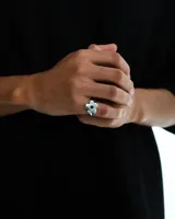 Anillo plateado de metal con forma de flor calada.