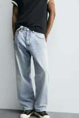 Pantalón de jean gris oscuro, corte amplio, con cinco bolsillos, efecto lavado y cierre frontal con cremallera y botón.