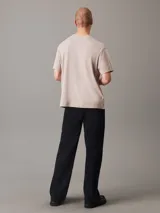 Remera color beige de corte regular, cuello redondo y mangas cortas. Presenta un monograma de Calvin Klein Jeans estampado en el pecho en color rojo y blanco.
