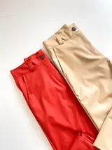 Pantalón de ecocuero rojo y beige, tiro alto y corte recto.