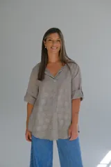 Blusa color visón con diseño de puntos en relieve, confeccionada en algodón. Tiene corte acampanado, escote en V y mangas 3/4 con botón para ajustar el largo.