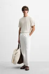 Pantalón de jogging color beige confeccionado en tejido de mezcla de algodón. Cuenta con cintura elástica ajustable con cordón, bolsillos frontales y traseros.