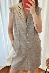 Vestido marrón con textura de lino, corte recto, sin mangas, cuello tipo blazer y cierre frontal con botones.
