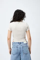 Remera corta negra de punto acanalado con escote en V fruncido y puntilla en el borde.