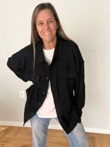 Sobrecamisa negra de pana fina con algodón, corte relajado, largo asimétrico, bolsillos delanteros y cierre de botones.