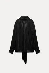 Blusa negra con cuello redondo con lazo en el mismo tejido, manga larga con puño y detalle de hilo metalizado.