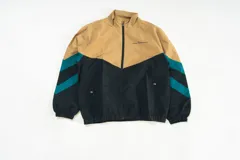 Campera deportiva Kaboa Industries de nylon liviano, color crema y negro, con paneles diagonales en contraste color verde azulado y micrográfico Kaboa aplicado al frente y en la espalda.