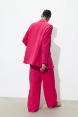 Blazer fucsia de cuello solapa y manga larga con hombreras. Detalle de tejido efecto arrugado. Bolsillos delanteros de vivo. Cierre frontal con un botón.