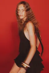 Vestido corto marrón con cuello halter que se ata con lazo, escote en pico, espalda descubierta y falda con volantes.