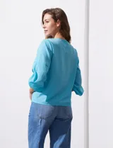 Blusa de gasa color blanco con estampado de hojas verdes, de mangas 3/4 abullonadas con puños elásticos.