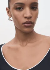 Camiseta ajustada de manga larga, color negro, con escote pico ribeteado en blanco.