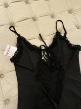 Minivestido negro con breteles finos, escote pronunciado con abertura y volados de tul transparente.