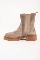 Bota Chelsea de gamuza color visón, con elásticos laterales y suela de goma color caramelo.