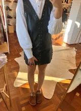 Minivestido negro de cuero sintético con escote en V, sin mangas y con tachas plateadas.