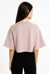 Remera cropped color rosa con cuello redondo, manga 3/4 y cierre frontal con broches.