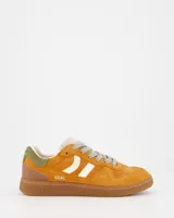 Championes deportivos Coolway modelo Goal, color naranja óxido con detalles en blanco, marrón y verde. Confeccionados en serraje suave con lengüeta preformada de piel, forro interior en piel, cordones planos de algodón bicolor intercambiables y suela flexible de goma y caucho.