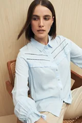 Camisa celeste de manga larga confeccionada en viscosa ligera, con detalles calados en la parte superior y pequeños volados.