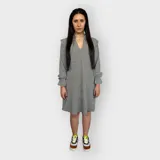 Vestido corto con estampado vichy en blanco y negro, escote en V, mangas largas con puños fruncidos y volados en los hombros.