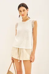 Musculosa blanca de lino con detalle de encaje en mangas y cuello. Tiene bordado de alas en el bajo.