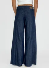 Pantalón de jean de corte ancho, color beige, con bolsillos delanteros y traseros.